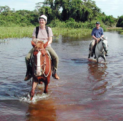 zwei Reiter auf Maultier im Fluss
